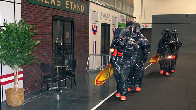 A group of emergency responders attending training at FEMA's Center for Domestic Preparedness (CDP) prepare to enter the CDP's mock subway train system through a simulated street scene used in training. These responders are part of the United States Army National Guard 140th Chemical Company from Lo