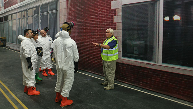 HEC instructor David Blaker (right) explains the training scenario to five HEC students. During the scenario, the students applied the information they learned during the course regarding the collection of evidence in a hazardous environment.