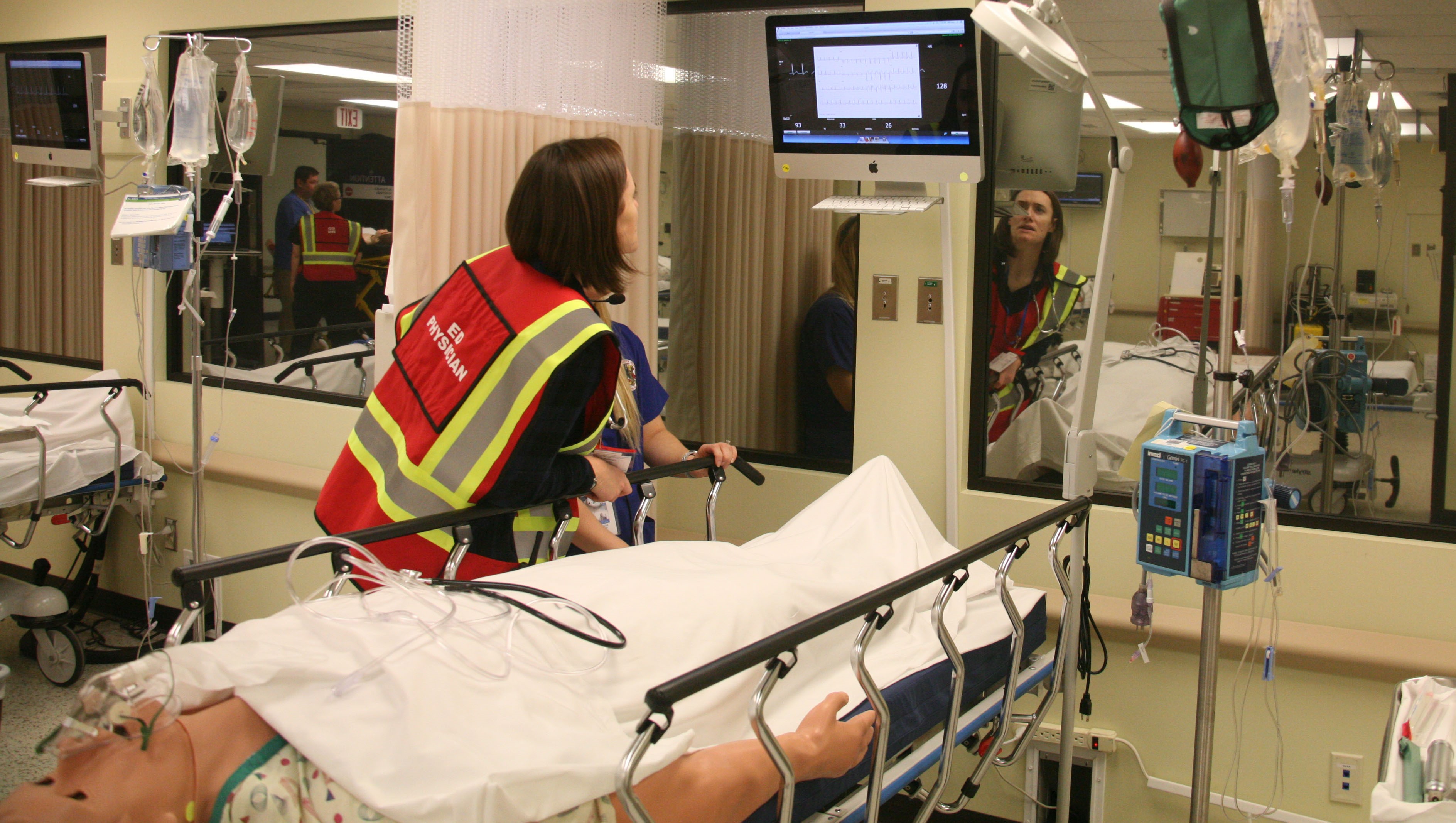 Student checking vitals of medical patient simulator in the emergency room during capstone mass casualty exercise.