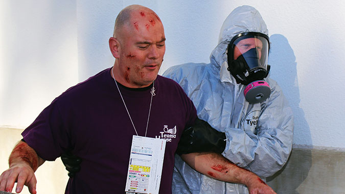 A student in the Emergency Medical Operations for CBRNE Incidents (EMO) course escorts a "survivor" from the incident scene during the Integrated Capstone Event (ICE).