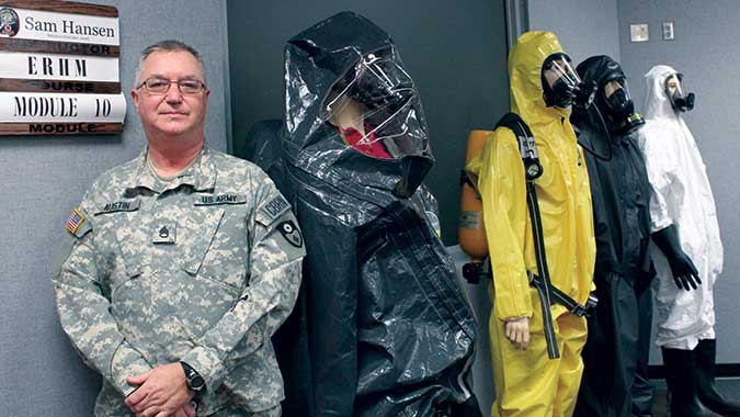Staff Sgt. John Austin, of the 149th Chemical Company, takes a break alongside some of the personal protective equipment used in the ERHM course.