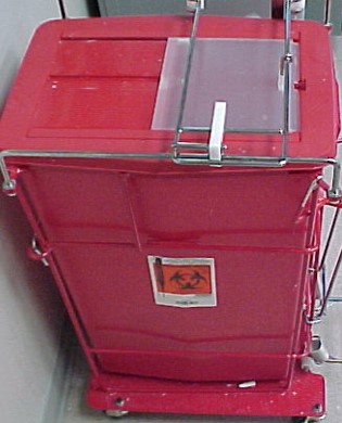 Image of a red rectangular container with a wire frame around it. On the front facing side of the front side of the plastic container is an orange biohazard symbols and the image of a syringe to the left of that.