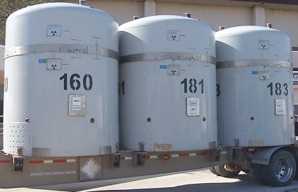 Image of a three gray cylindrical radioactive materials containers on a trailer.